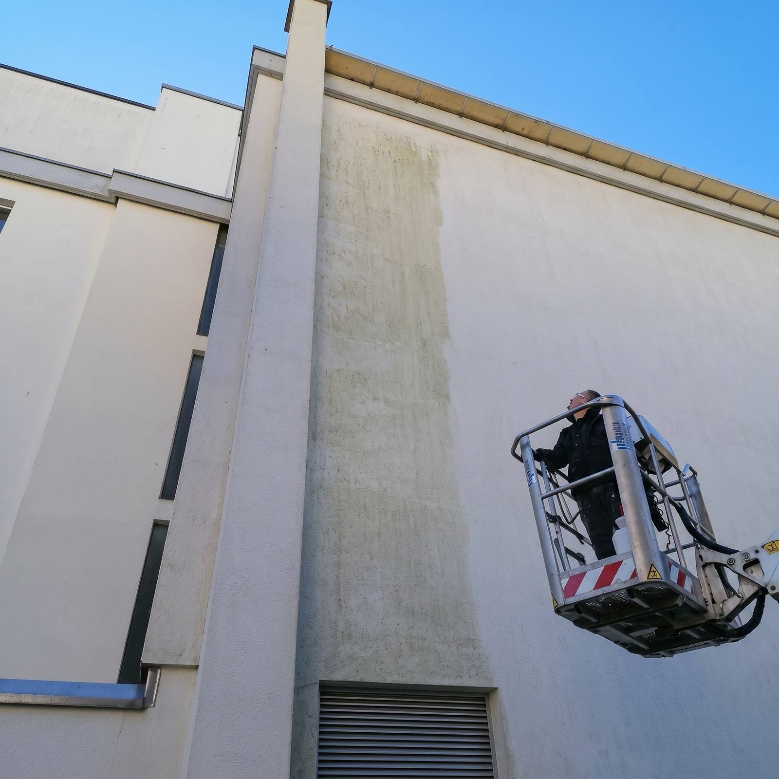 Operatore FY al lavoro sulla facciata con cestello elevatore